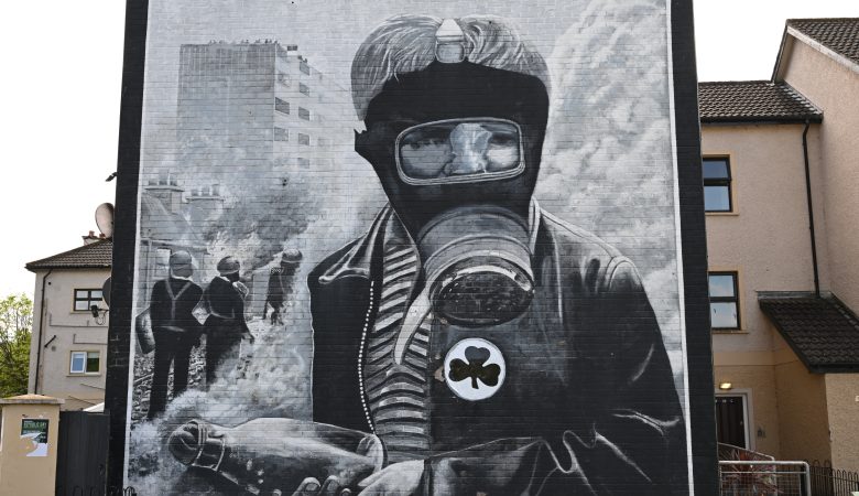 Mauerbild aus dem Nordirlandkonflikt, Derry, Junge mit Gasmaske und Shamrock an der Jacke
